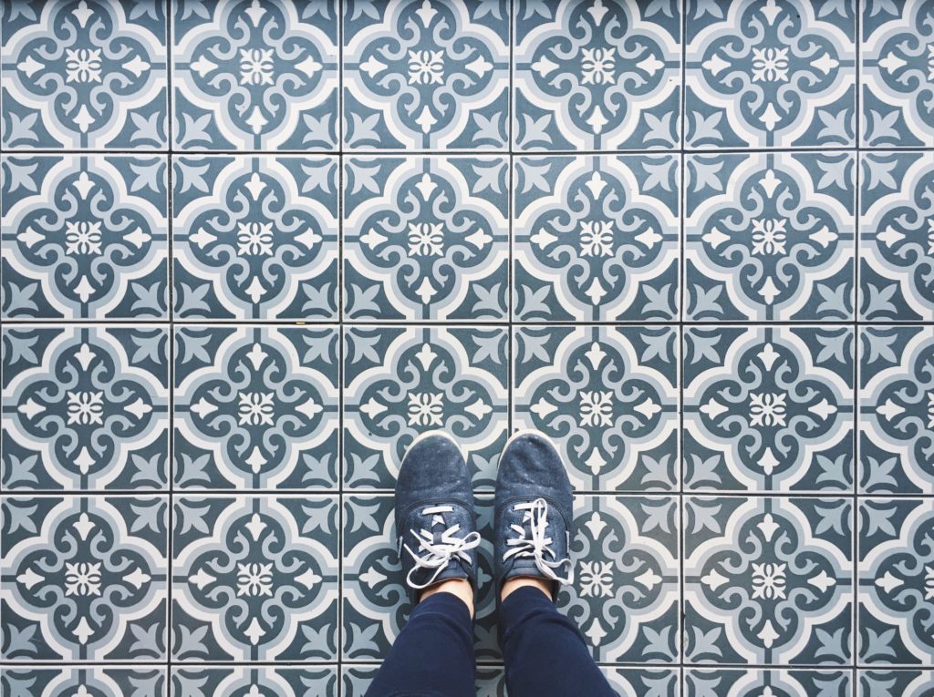 Woman's feet with shoes on patterned tile floor