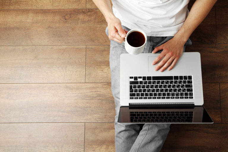 Man with coffee and laptop on hardwood