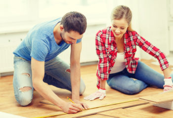 DIY Wood Floors featured image of a couple measuring wood planks