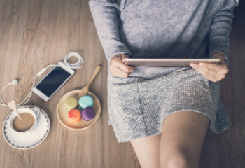Ash flooring featured image of a woman sitting on the ground with coffee, phone, cookies, and tablet